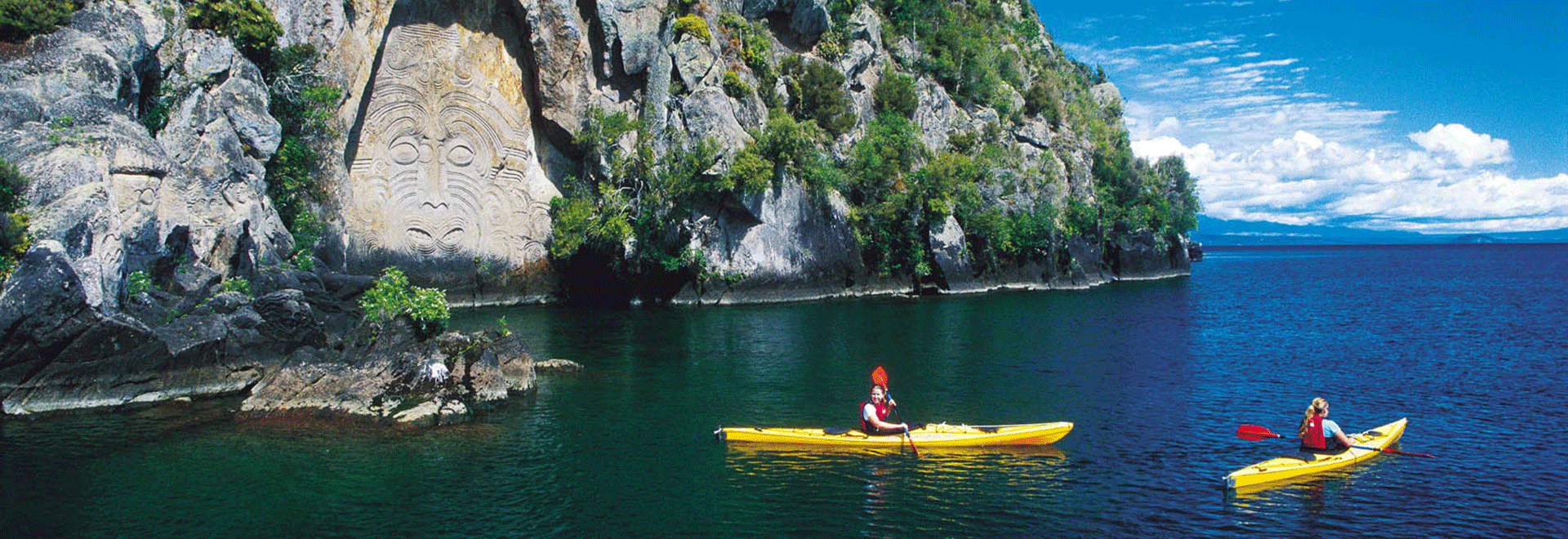Image of kayaks on the water next to rock carvings